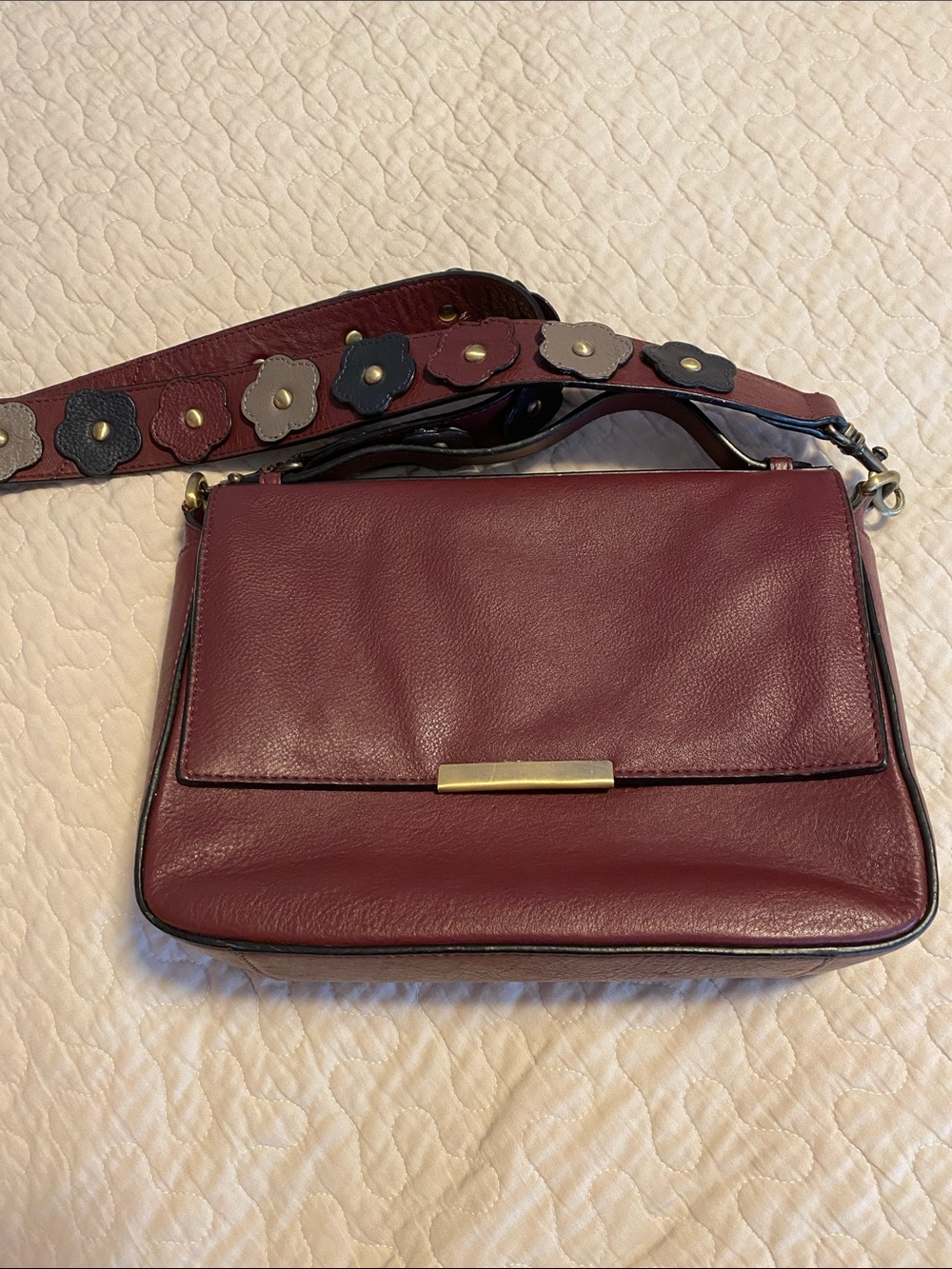 Paradox burgundy leather crossbody with removable appliquéd strap.